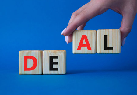 Deal symbol. Concept word Deal on wooden cubes. Businessman hand. Beautiful blue background. Business and Deal concept. Copy space.の写真素材