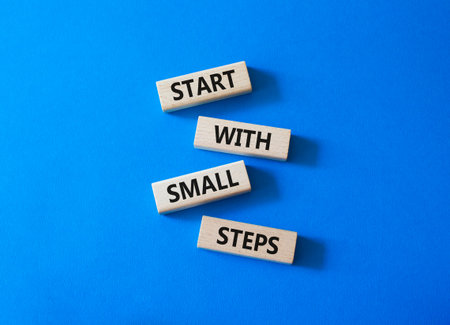 Steps symbol. Concept words Start with Small Steps on wooden blocks. Beautiful bright blue...