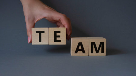 Team symbol. Concept word Team on wooden cubes. Businessman hand. Beautiful gray background....