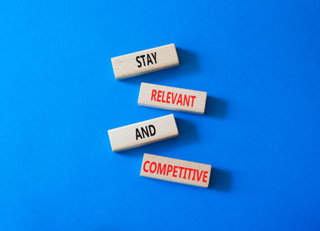 Relevant and Competitive symbol. Concept words Stay Relevant and Competitive on wooden blocks. Beautiful bright blue background. Business and Stay Relevant and Competitive concept. Copy space.の写真素材