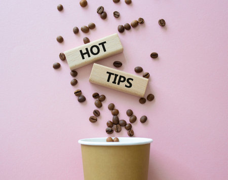 Hot Tips symbol. Concept word Hot Tips on wooden blocks. Beautiful pink background with coffee cup....