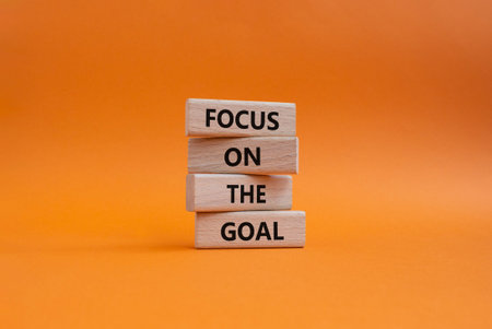 GOAL symbol. Wooden blocks with words FOCUS ON THE GOAL. Beautiful orange background. Business and GOAL concept. Copy spaceの写真素材