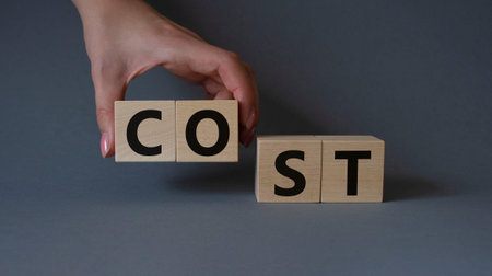 Cost symbol. Concept word Cost on wooden cubes. Beautiful gray background. Businessman hand. Business and Cost concept. Copy space.の写真素材