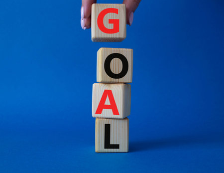 Goal symbol. Concept word Goal on wooden cubes. Beautiful blue background. Businessman hand....