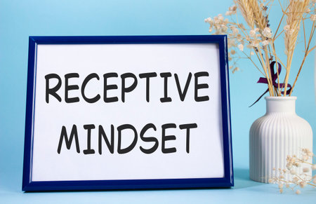 Receptive Mindset symbol. Concept words Receptive Mindset on beautiful wooden picture frame. Beautiful light blue background with flower vase. Business and Receptive Mindset concept. Copy space.の写真素材