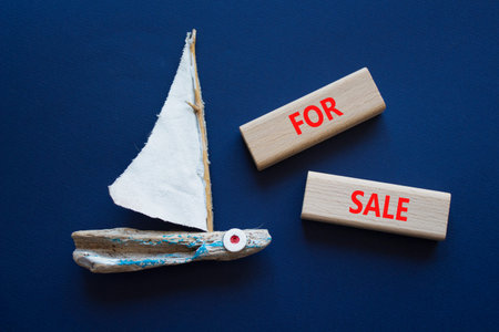 FOR SALE symbol. Concept word FOR SALE on wooden blocks. Beautiful deep blue background with boat....