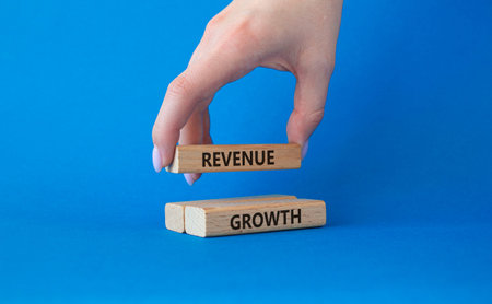 Revenue growth symbol. Concept word Revenue growth on wooden blocks. Businessman hand. Beautiful...
