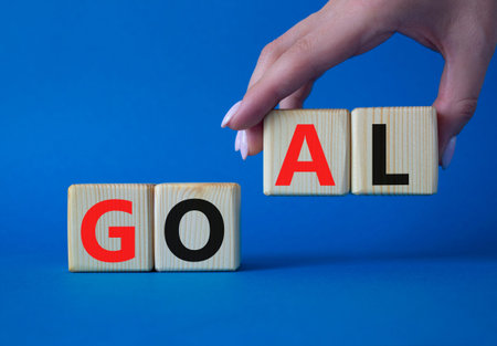 Goal symbol. Concept word Goal on wooden cubes. Beautiful blue background. Businessman hand. Business and Goal concept. Copy space.の写真素材