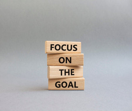 GOAL symbol. Wooden blocks with words FOCUS ON THE GOAL. Beautiful gray background. Business and...