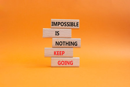Keep Going symbol. Wooden blocks with words Impossible is Nothing Keep Going. Beautiful orange...
