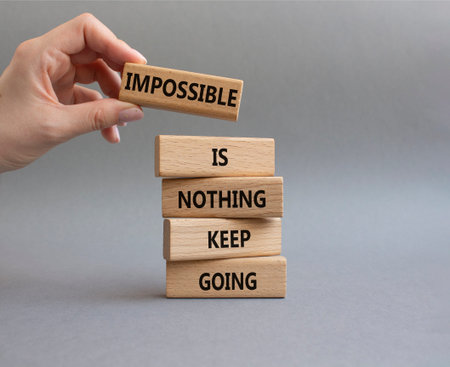 Keep Going symbol. Wooden blocks with words Impossible is Nothing Keep Going. Businessman hand....