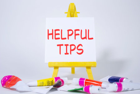 Helpful tips symbol. Wooden blocks with words Helpful tips. Beautiful white background with paints...