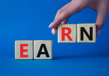 Earn symbol. Concept word Earn on wooden cubes. Businessman hand. Beautiful blue background. Business and Earn concept. Copy space.の写真素材