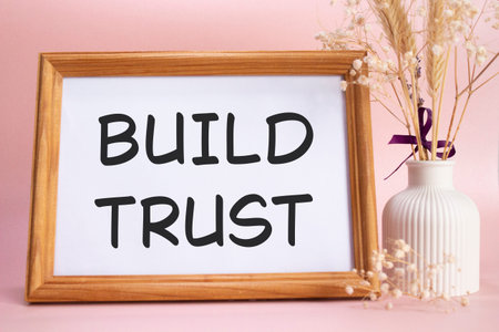 Build trust symbol. Concept words Build trust on beautiful wooden picture frame. Beautiful pink...