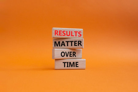 RESULTS symbol. Wooden blocks with words RESULTS MATTER OVER TIME. Beautiful orange background....