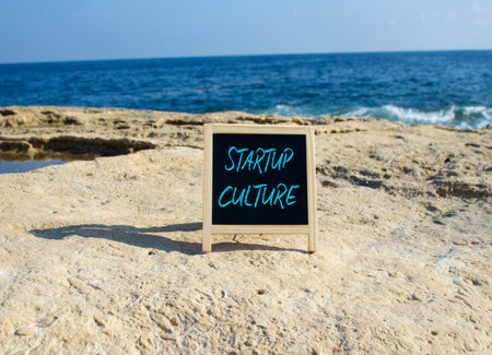 Startup Culture symbol. White blackboard with Concept words Startup Culture. Beautiful sea background. Business and Startup Culture concept. Copy space.