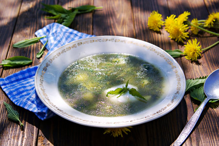 Hot nettle and sorrel soup with potatoes and sour cream in a vintage plate on a brown wooden background. Recipes with wild herbs.の写真素材