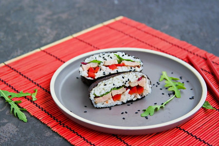 Sushi sandwiches with baked duck, spinach and sweet pepper on a brown clay plate on a dark concrete background. Japanese food.の写真素材