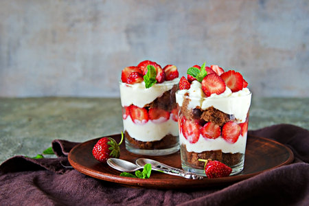 Dessert, truffle with chocolate biscuit, fresh strawberries and custard or cream cheese in glasses on a gray concrete background. Berry desserts recipes. Valentines day concept.の写真素材