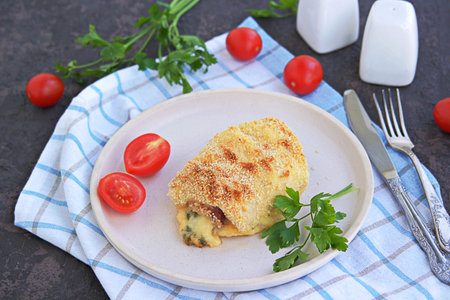Homemade fillet Cordon or chicken fillet with ham and cheese on a white clay plate on a dark brown...