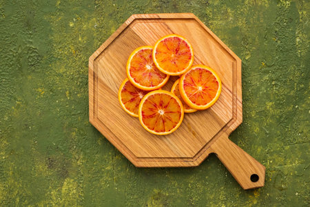 Sliced Sicilian bloody oranges on a wooden board on an olive green background. Citrus fruit.の写真素材