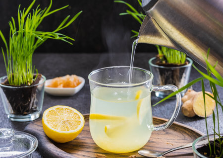 Ginger tea with lemon in a glass mug on a dark concrete background. Hot drink recipes.の写真素材