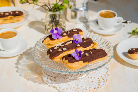 Dessert, choux pastry sweets with vanilla custard, covered with chocolate glaze, on a glass stand on...