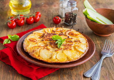 Spanish tortilla, traditional dish with eggs and fried potatoes on a clay plate on a wooden background. Potato recipes. Thanksgiving dayの写真素材