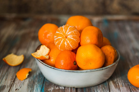 Juicy tangerines in a gray ceramic bowl on a wooden background. Selective focus.の写真素材