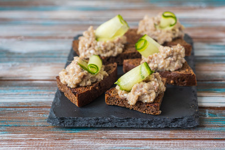 Appetizer, herring, onion and boiled egg forshmak on fried rye bread on a slate or stone board on a...