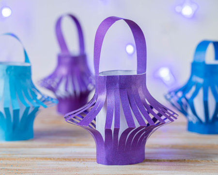 Home decoration, purple and blue paper lanterns and purple garland on a wooden background. Children's creativity, craft, DIY. New Year's decoration made of paper.の写真素材