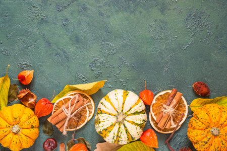 Festive autumn decor of pumpkins, spices, leaves and dried flowers on a green concrete background. Autumn composition with place for text. Thanksgiving, Halloween holiday concept. top viewの写真素材