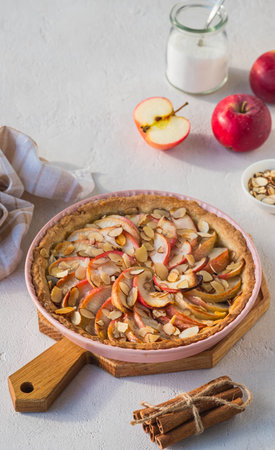 Dessert, round apple pie or shortcrust pastry tart with apple slices and almond petals in a pink shape on a light concrete background. Thanksgiving day concept. Apple Pie Recipesの写真素材