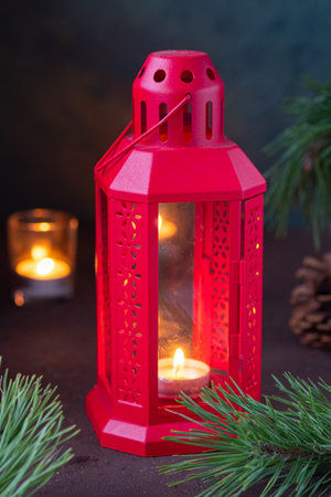 Festive composition, red metal lantern with a candle and fir branches on a brown concrete background. Merry christmas concept. Winter holidaysの写真素材