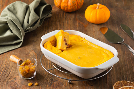 Cottage cheese casserole with pumpkin and raisins in a rectangular baking dish on a brown wooden background. pumpkin recipes.の写真素材