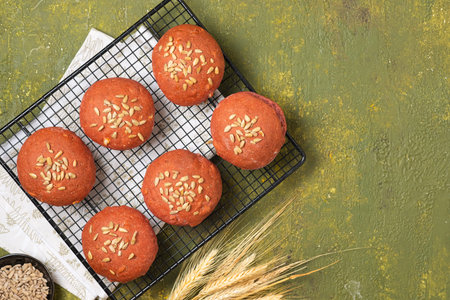 Bread buns made from rye and wheat flour with beetroot puree and sunflower seeds on a baking grate...