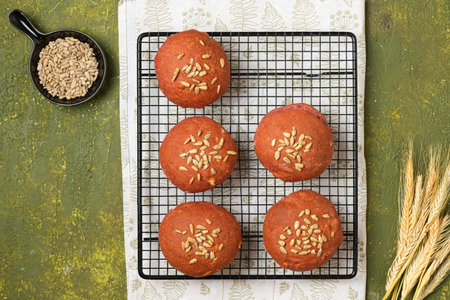 Bread buns made from rye and wheat flour with beetroot puree and sunflower seeds on a baking grate...