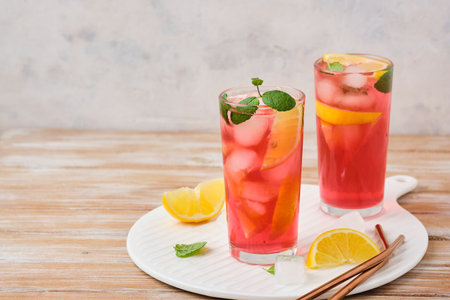 Pink cold lemonade from hibiscus tea with lemon slices and ice cubes in glasses on a wooden background. Refreshing soft drinks. summer drinksの写真素材