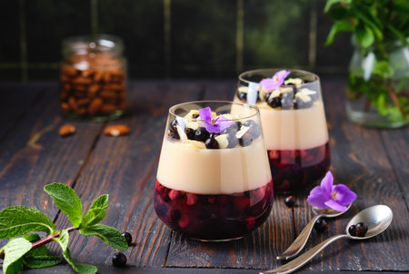 Two-layer jelly with a berry layer and a layer of almond milk panna cotta in transparent glasses on a dark wooden background. Vegan, desserts without baking. Desserts in a glass.の写真素材