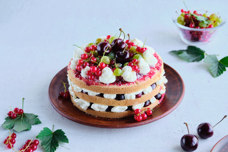 Summer cake with custard, raspberry jam and assorted berries on a clay plate on a light concrete background. Summer cakes with berries.の写真素材