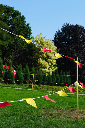 Yellow and red triangular flags strung in the park. Activities in parks, outdoors. parks, natureの写真素材