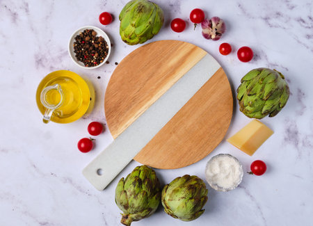 Culinary background with artichokes, seasonings, cheese, garlic and olive oil on a light background with space for text. Top view.の写真素材