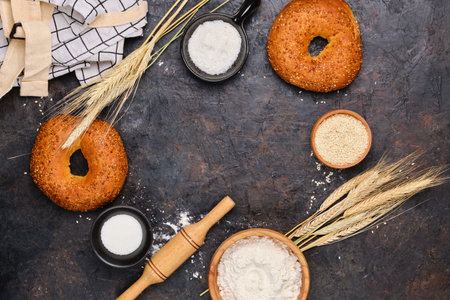 Culinary background with fresh bagels and baking ingredients on a black concrete background with space for text. Top view.の写真素材