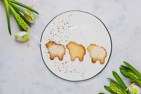 Easter baking, three lamb cookies made from shortcrust pastry with sugar on a white round ceramic...