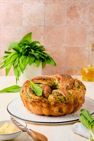 Unsweetened pastries, round snack twisted bread with wild garlic pesto on a white dish on a light concrete background. Ramson recipes. Unsweetened baked goodsの写真素材