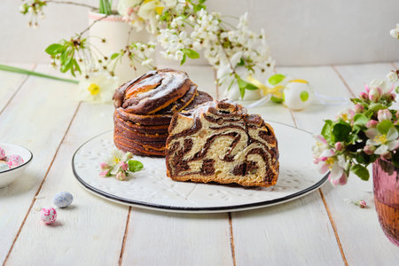 Two-layer vanilla chocolate Easter yeast cake craffin on a ceramic board on a light wooden...