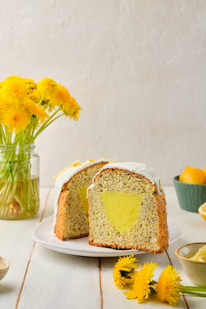 Cut cake with lemon filling and poppy seeds, covered with sugar icing, on a ceramic plate on a light...
