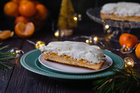 Cut Christmas mini tart with mandarin filling and cream on green plate on dark wooden background. Holiday desserts. Merry Christmasの写真素材