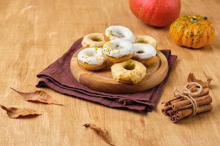 Baking, pumpkin donuts with sugar glaze on wooden board on wooden background. Baking with pumpkin. Thanksgiving Day conceptの写真素材