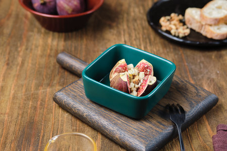 Baked figs stuffed with blue cheese and walnuts in a portioned ceramic form on a wooden background. Fig recipes. Seasonal productsの写真素材